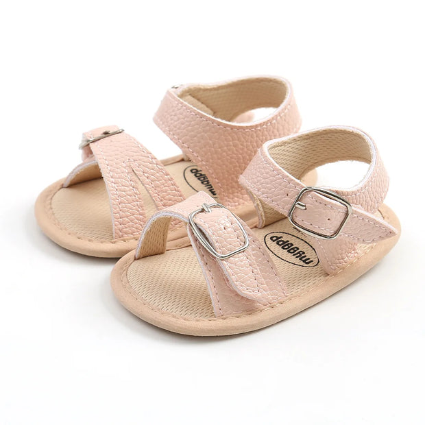 Pair of pink baby sandals with buckles on a white background