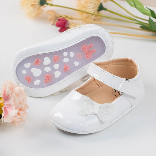 White children's shoes with a bow and floral design on a light background