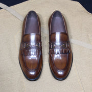 Pair of brown loafers with decorative buckle on a beige surface