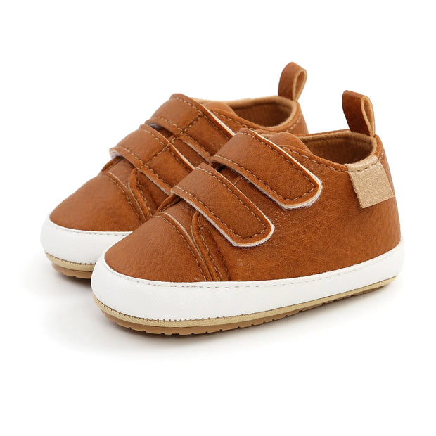 Pair of brown children's shoes with white soles on a white background