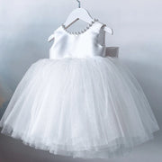 White dress with a layered tulle skirt on a hanger against a light gray background