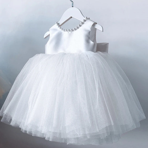 White dress with a layered tulle skirt on a hanger against a light gray background