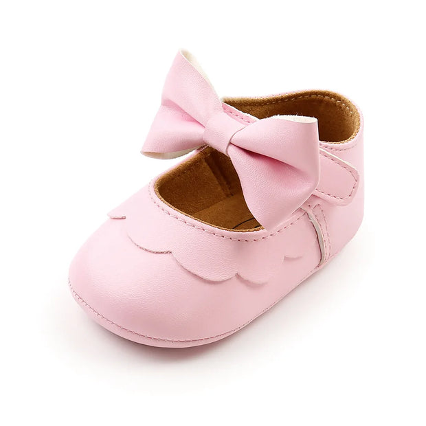 Pink baby shoe with a bow on a white background
