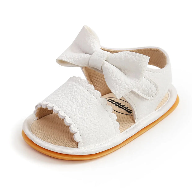 White baby sandal with a bow on a white background