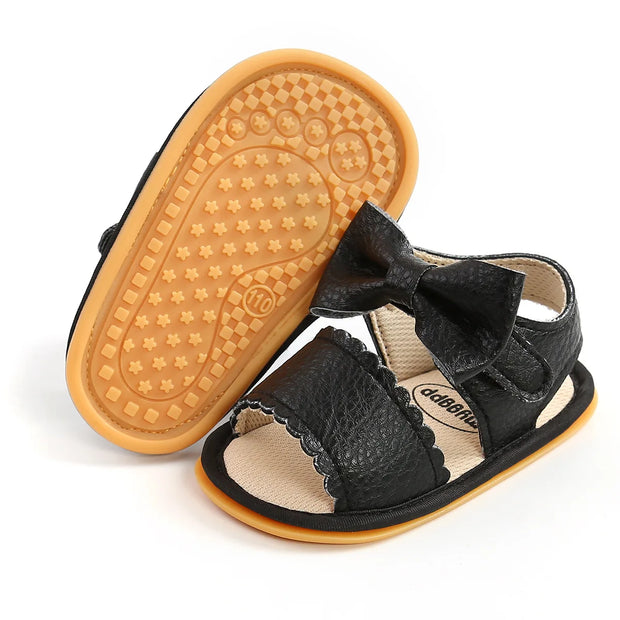 Black sandal with bow and tan sole on a white background