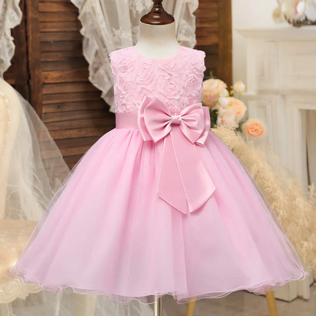Pink lace dress with a large bow on a mannequin against a decorative background.