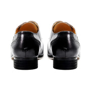 Black dress shoes with brown soles on a white background