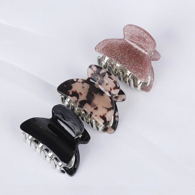 Set of four hair clips in black, tortoiseshell, and rose gold on a white background