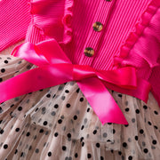 Pink cardigan with a large pink bow and polka dot dress underneath