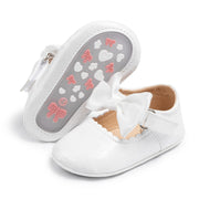 White baby shoes with a bow on a white background