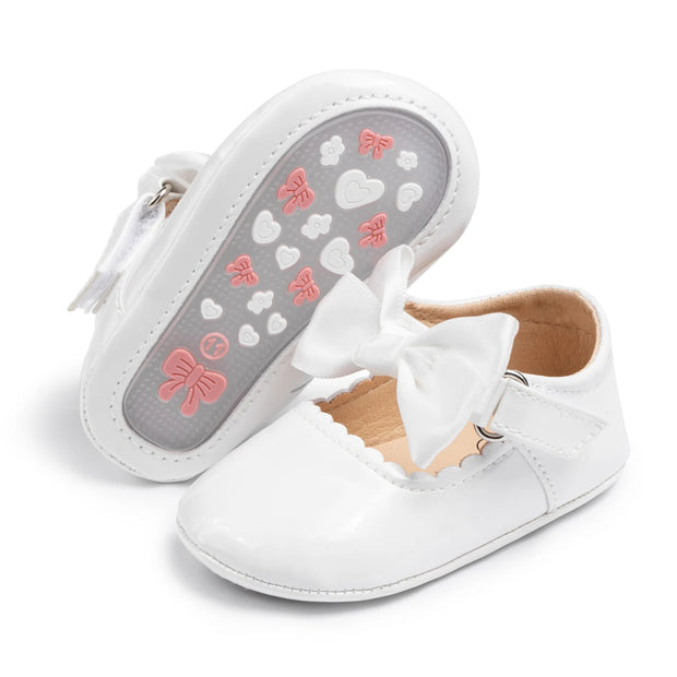 White baby shoes with a bow on a white background