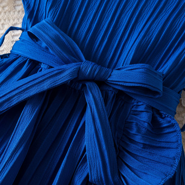 Close-up of a blue dress with a tie detail on a textured surface