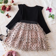 Black long-sleeve top with a sheer polka dot skirt on a textured surface with flowers and butterflies.
