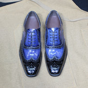 Pair of blue and black shiny dress shoes on a beige fabric background