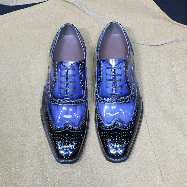 Pair of blue and black shiny dress shoes on a beige fabric background