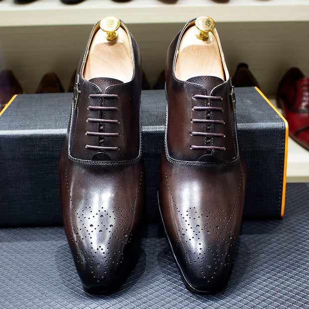 Pair of brown leather dress shoes on a textured surface with blurred background