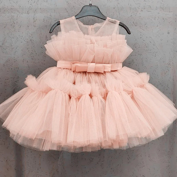 Pink tulle dress with a bow on a hanger against a gray background