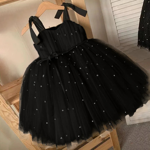 Black tulle dress with rhinestone embellishments on a wooden hanger.