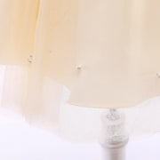 Close-up of a beige garment with pearl-like embellishments on a white background