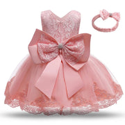 Pink lace dress with a large bow and matching headband on a white background