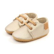 Pair of beige baby shoes with brown laces on a white background
