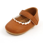 Brown baby shoe with a strap on a white background