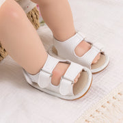 White sandals worn by a child on a soft surface