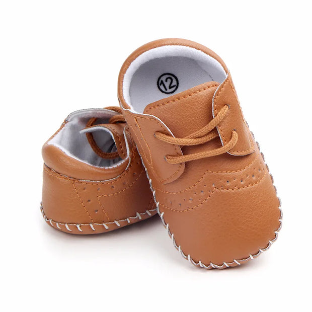 Pair of brown baby shoes with white laces on a white background