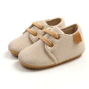 Beige baby shoes with brown accents on a white background