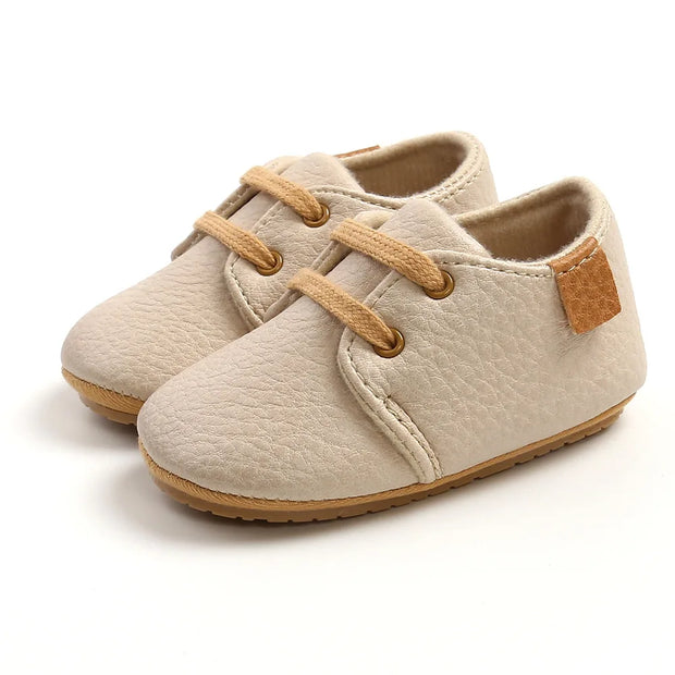 Beige baby shoes with brown accents on a white background