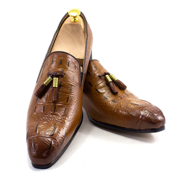 Pair of brown crocodile skin loafers with tassels on a white background