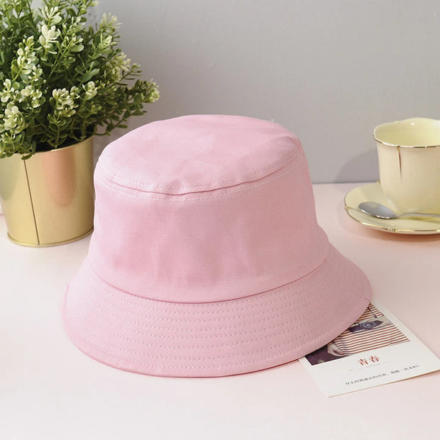 Pink bucket hat on a table with a plant and tea set in the background