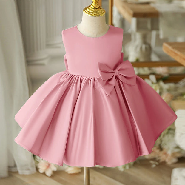 Pink dress with a bow on a mannequin against a blurred indoor background