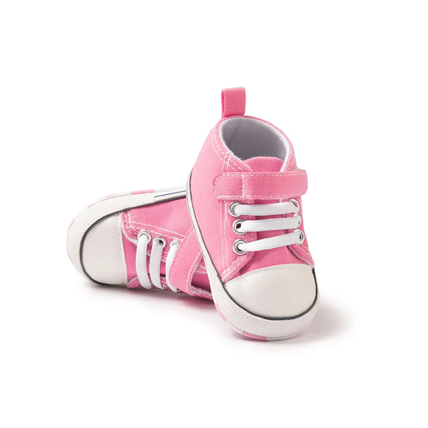 Pink baby sneakers with white laces on a white background
