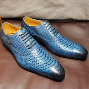 Blue textured dress shoes with yellow lining on a brown surface