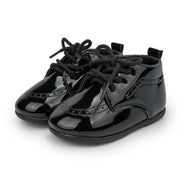 Pair of black patent leather shoes with laces on a white background
