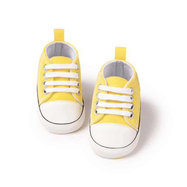 Pair of yellow baby sneakers on a white background