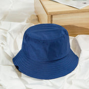 Blue bucket hat on a white fabric surface with a wooden table in the background