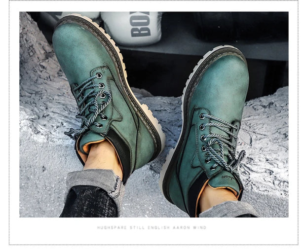 Green leather boots worn with gray pants on a rocky surface.