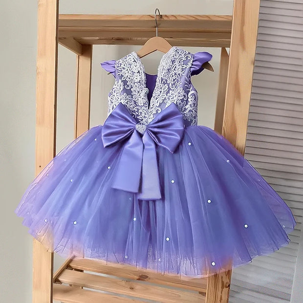 Purple children's dress with lace top and bow on a wooden hanger