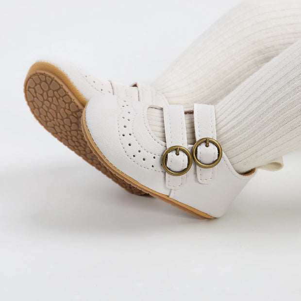 White shoe with brown sole and gold circular details on a white background