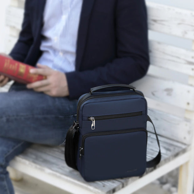 Navy blue backpack on a bench with a person reading a book in the background