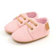 Pink baby shoes with brown accents on a white background