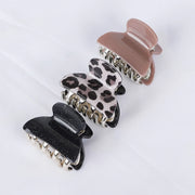 Three hair clips in black, leopard print, and pink on a white background