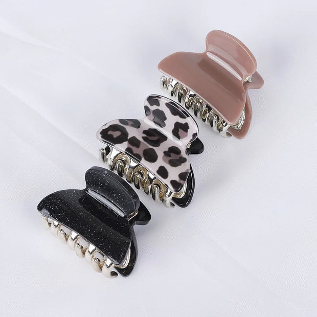 Three hair clips in black, leopard print, and pink on a white background