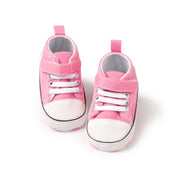 Pair of pink baby sneakers with white soles on a white background