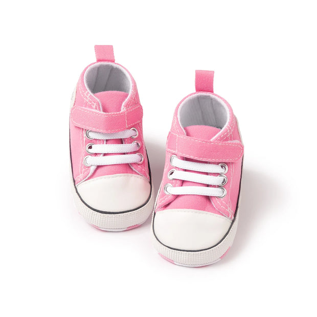 Pair of pink baby sneakers with white soles on a white background