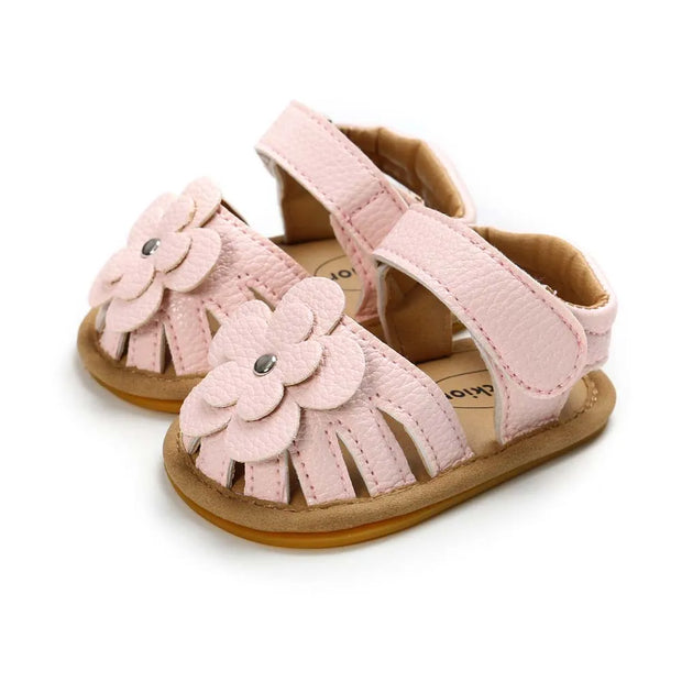 Pink baby sandals with flower details on a white background