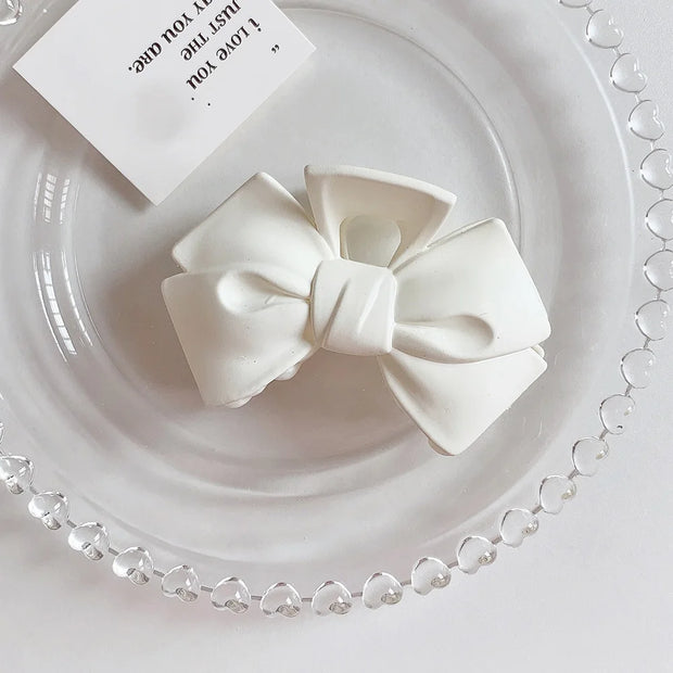 White bow-shaped object on a decorative white plate with heart patterns