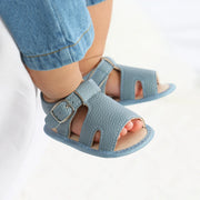 Blue sandals with a strap worn by a person on a white background